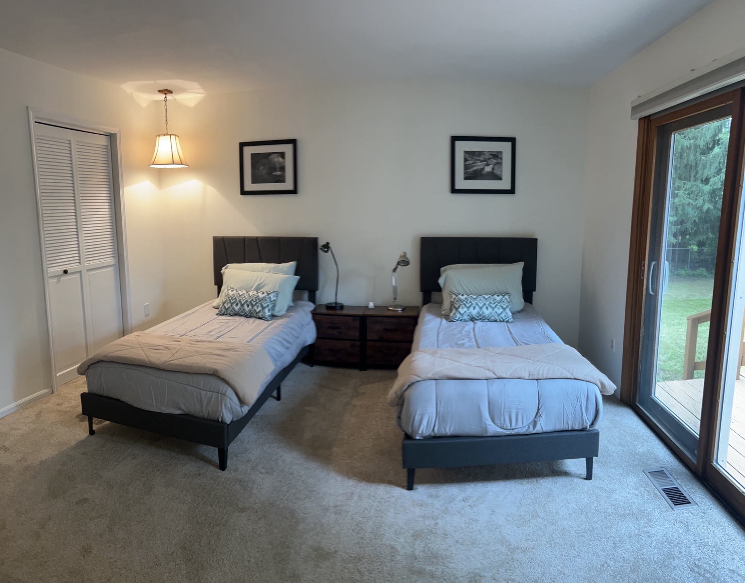 Spacious shared bedroom with two beds, bedside storage, and backyard access