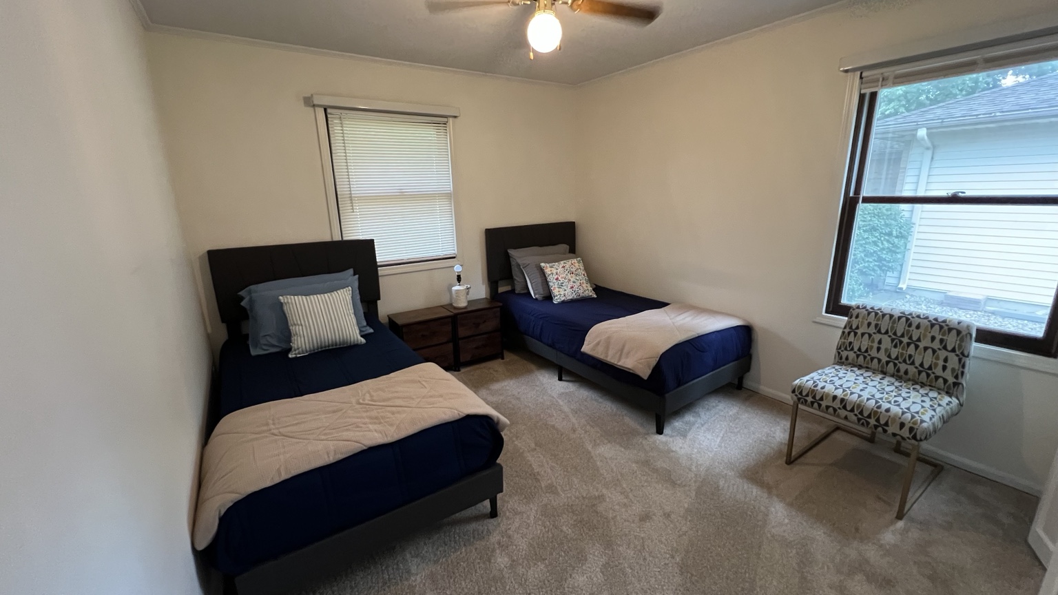 Shared bedroom with two blue beds, bedside storage, and a sitting chair