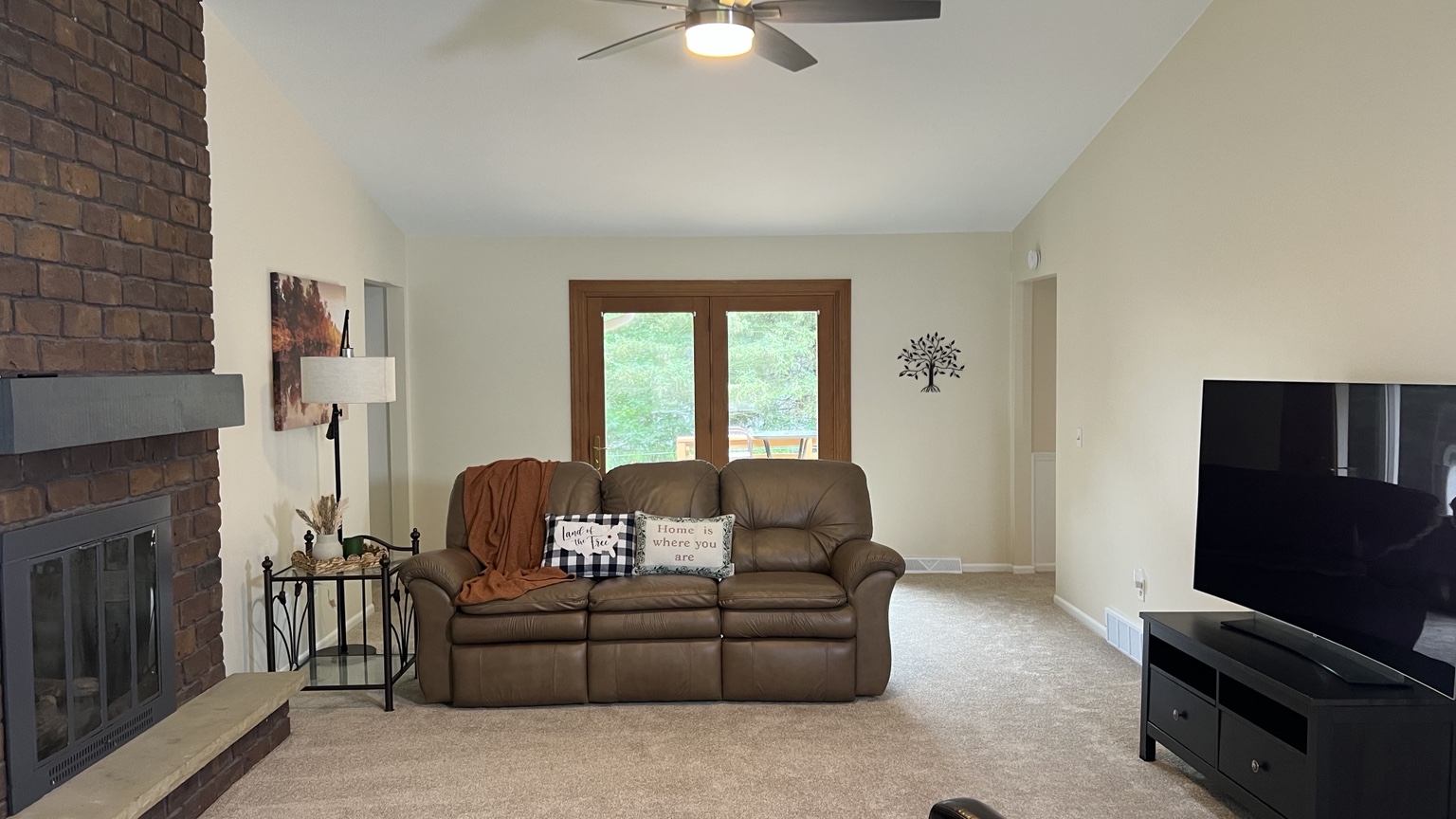 Spacious living room with a sofa, television, fireplace, and backyard doors