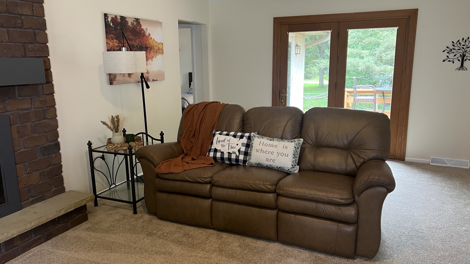 Comfortable living room sofa beside the brick fireplace and backyard doors